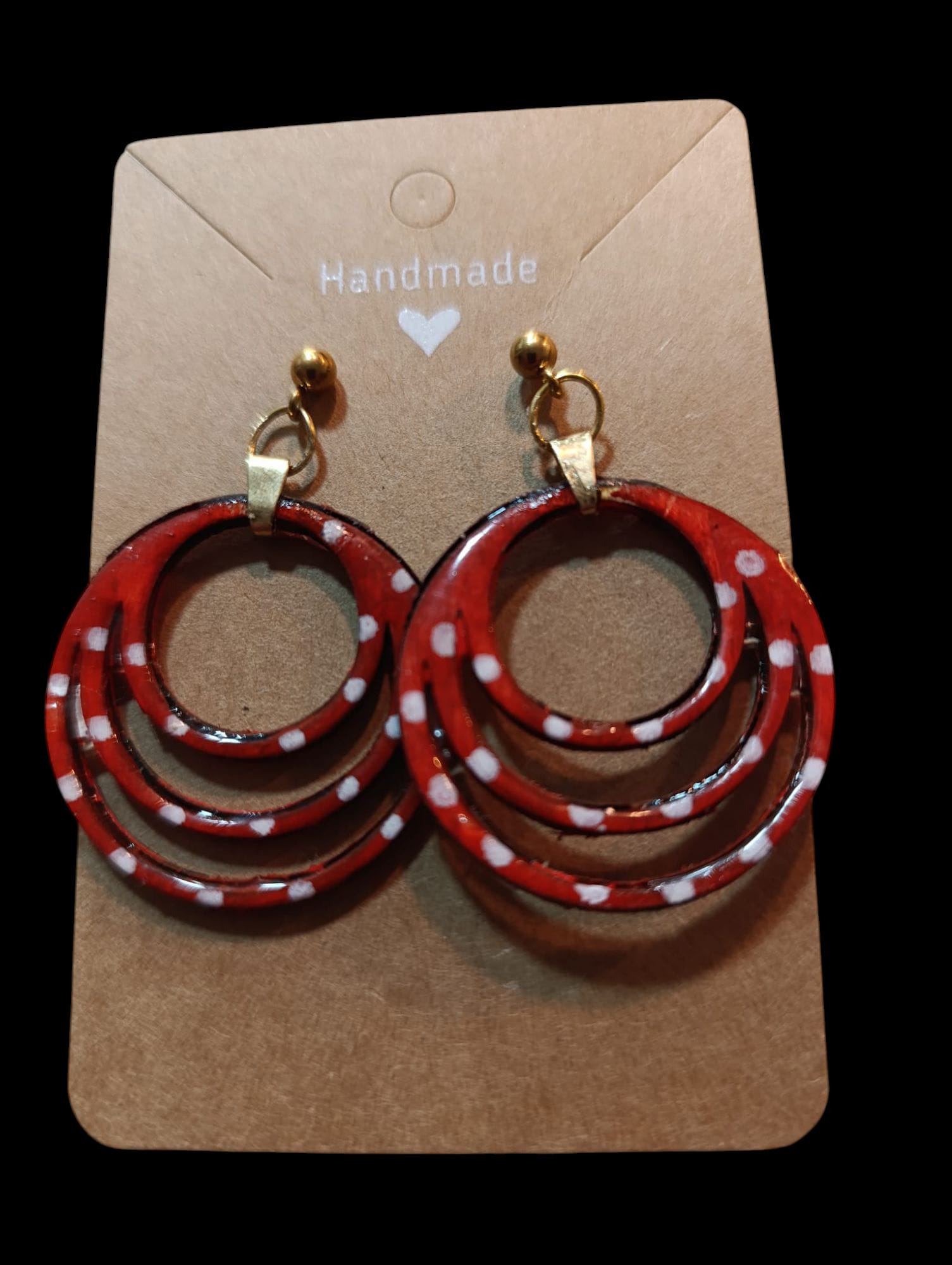 Pendientes artesanales de madera modelo Sevilla con círculos concéntricos rojos y lunares blancos.