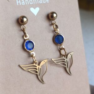 Pendientes colibrí con cristal azul en fondo marrón