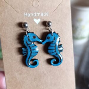 Pendientes de caballitos de mar en color azul sobre una tarjeta de presentación.