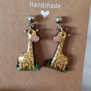 Pendientes de jirafa en color amarillo con detalles pintados a mano sobre fondo marrón claro.